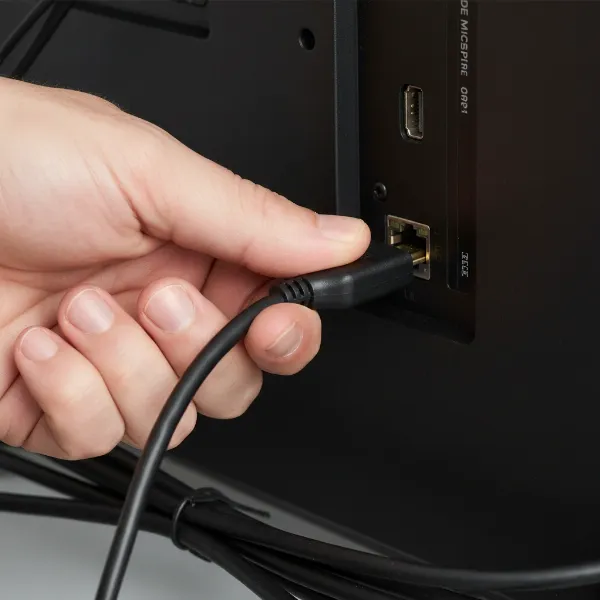 A hand checking a firmly connected HDMI cable into a port on a device.